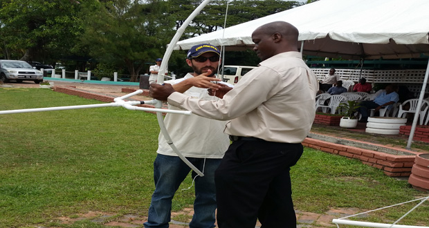 Permanent Secretary Alfred King is taught how to use the recently constructed PVC bow by coach Diego Torres.