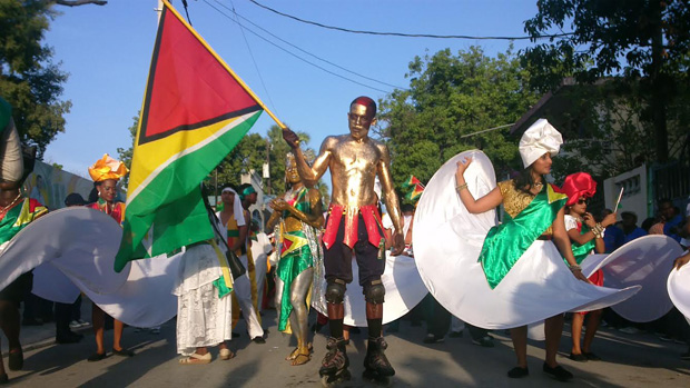 A Haitian national carrying the Guyana flag leads the country's delegation through Magloire Ambrose Avenue on Friday