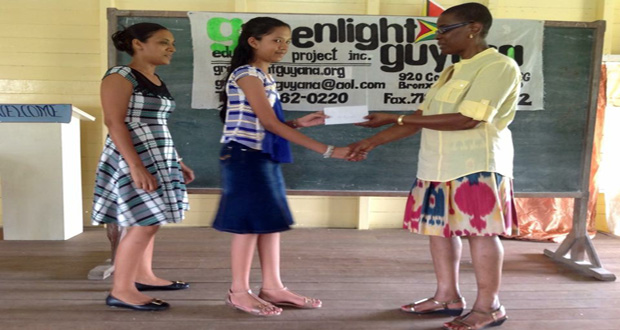 GreenLight Guyana Founder, Ms. Salome Osborne, presenting an award to one of the two best graduating pupils of La Retraite Primary, Bibi Hamid.  Looking on at left is Bibi’s mom, Mrs. Hamid