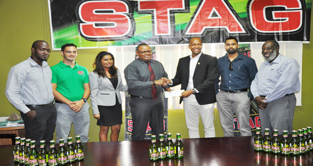 Ansa McAl’s Marketing Director Troy Cadogan, makes a symbolic presentation to GFF Normalisation Committee Chairman Clinton Urling while other officials and representatives of the company look on.