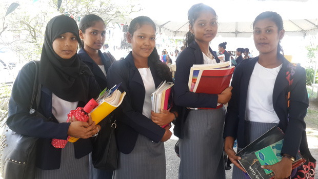 Students from Queen’s College and Cyril Potter College of Education posing with their new collection of books
