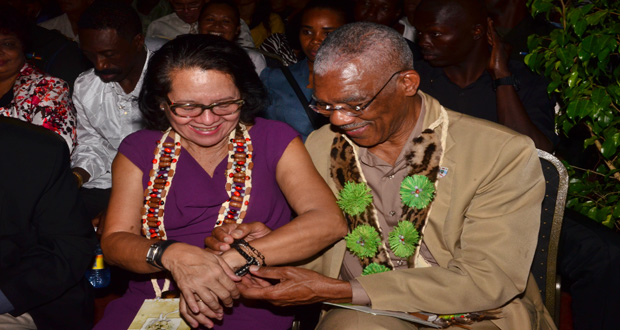 President David Granger ties the symbolic indigenous marriage band on First Lady Sandra Granger’s wrist. The ‘marriage band’ was presented to the First Lady by an Amerindian girl, during Tuesday’s launch of Heritage Month (Adrian Narine photo)