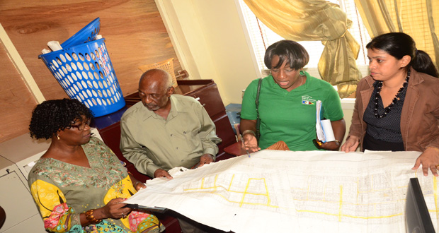 Minister Scott and staffers of the Housing Department examining a plan for refurbishing of the accommodation of the Department in Region 5