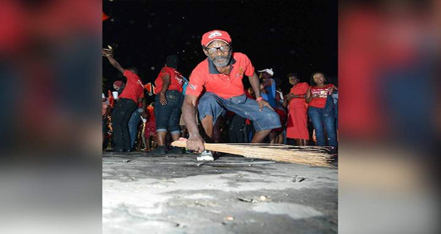 CLEANING UP: A People's National Movement (PNM) supporter sweeps with a cocoyea broom outside Balisier House last night after the party was victorious in the general election. (Photo by CURTIS CHASE)