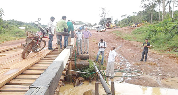 Ministers Ronald Bulkan and David Patterson, along with engineers and regional officials inspecting an illegal connection and the pressure of the water at Mahdia