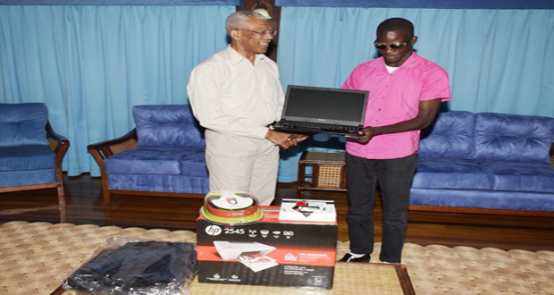 President David Granger handing over the laptop and ancillary equipment to visually impaired UG student, Ceion Rollox yesterday at the Ministry of the Presidency