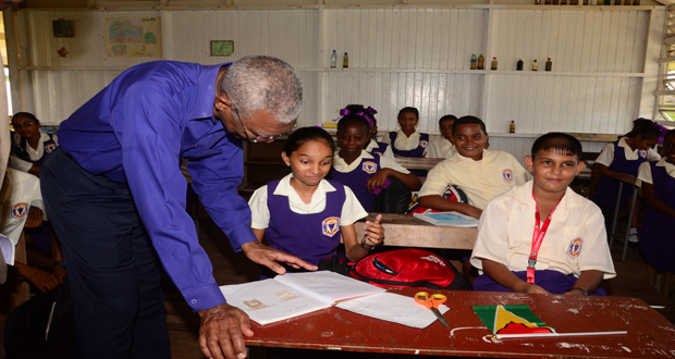 President David Granger looks through an exercise book belonging to Bhagmattie Charran.