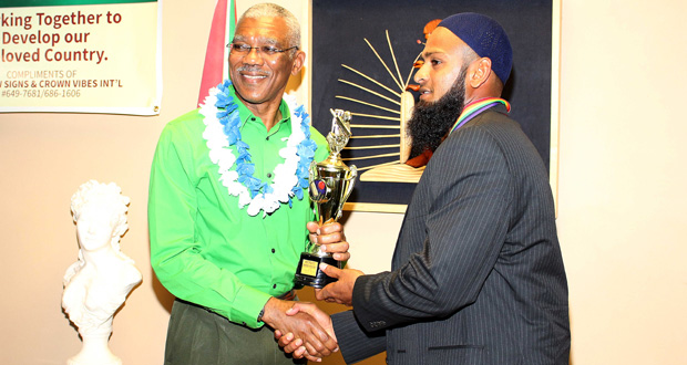 President David Granger (right) presents the award to West Indies Test player Assad Fudadin.