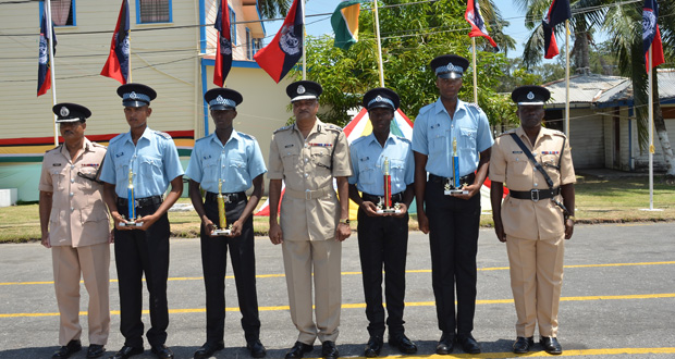 Top performers  from recent police training courses (with trophies)  pose with Police Commissioner Seelall Persaud (centre) , Assistant Commissioner David Ramnarine (left) and Senior Superintendent Paul Williams, Force Training Officer (right).