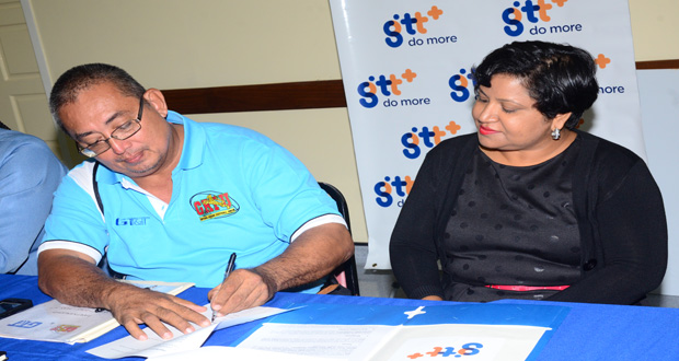 GRFU president Peter Green signs the MOU while GT&T's Senior Marketing Executive Anjanie Hackett looks on. (Adrian Narine photo)