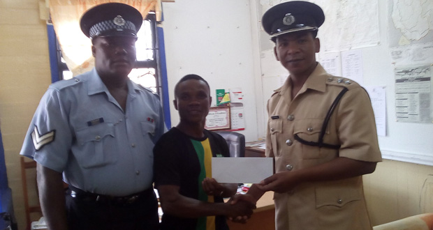Police Commander of 'E'Division Superintendent Calvin Brutus hands over sponsorship cheque to Orlan 'Pocket' Rogers for Saturday night's amateur boxing card at the New Silvercity Secondary School hard court in Linden