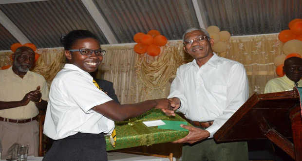 Elisa Hamilton being presented with a laptop computer by President David Granger