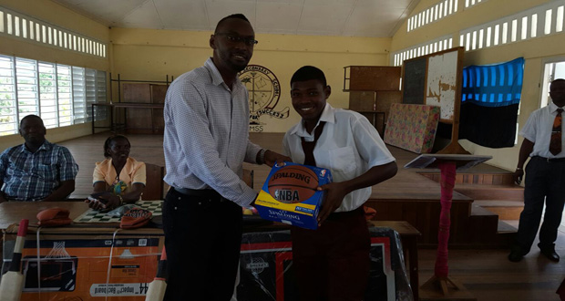 Director of Sport Chris Jones hands over a basketball to one of the students of Three Miles Secondary