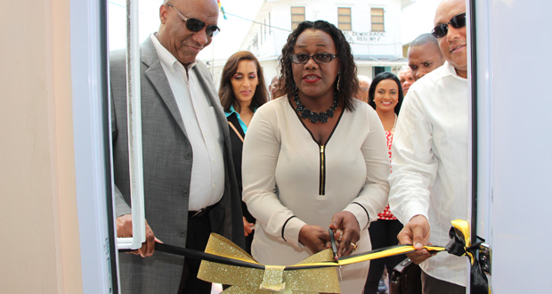 Minister Simona Broomes cuts the ribbon to recommission the GGB's Bartica Office, while Ministers Harmon and Trotman look on