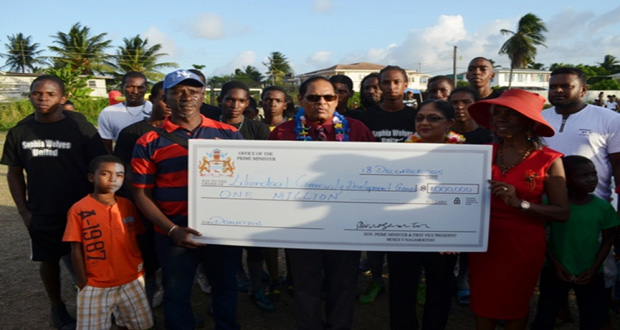 Prime Minister Moses Nagamootoo and wife Sita Nagamootoo hand over the cheque to founder of the Liliendaal Community Development Group, Beryl Haynes, in the presence of the community members