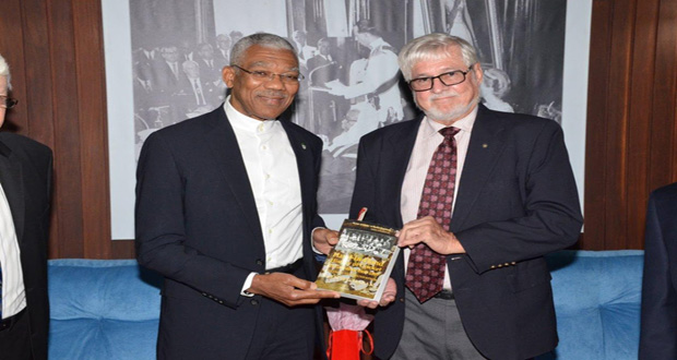 President David Granger receives a copy of ‘Hand-in-Hand History of Cricket in Guyana 1865-1897’ from the insurance company’s Board member John Carpenter.