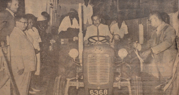 A step forward:  Mr Randolph Cheeks, Minister of Local Government, cuts the ribbon, and the new $4,600 tractor and trailer acquired by Lodge Village Council is set in motion. It was intended to be used to collect garbage in the village. (January 6, 1966)
