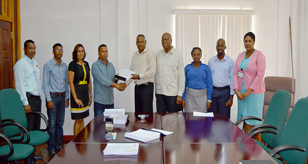 BNTF Project Manager Michael Singh hands over the contract to N Lachman – the CEO of N Lachman Business Establishment & Civil Works in the presence of Finance Secretary Dr Hector Butts and other officials