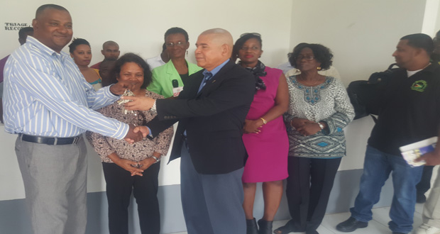 Project Manager of the BNTF, Michael Singh, hands over the keys for the new health centre to Minister of Public Health, Dr George Norton, in the presence of APNU/AFC Parliamentarian Jennifer Wade and other officials