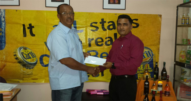 YWCC senior coach Hubern Evans receives the sponsorship cheque from Marketing Representative Imran Khan.