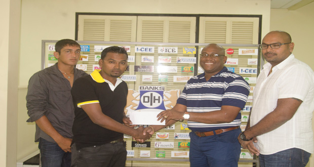 Banks DIH Limited Clive Pellew hands over the cheque to Shabeer Baksh in the presence of Gavin Jodhan and Zameer Inshan.