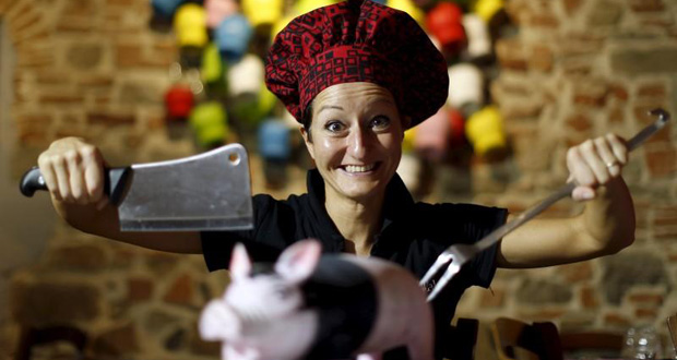 Italian chef Cristina Palanti poses with a meat cleaver and cooking fork hovering over a plastic pig figurine at the "L'e'Maiala" restaurant in Florence in this October 6, 2012 file photo. (REUTERS/Alessandro Bianchi/files)