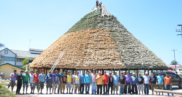 Toshao Paul Chekema (centre) and Advisor on Indigenous People’s Affairs, Mervyn Williams, with members of the team working on the conical palm-thatched roof of the Umana Yana