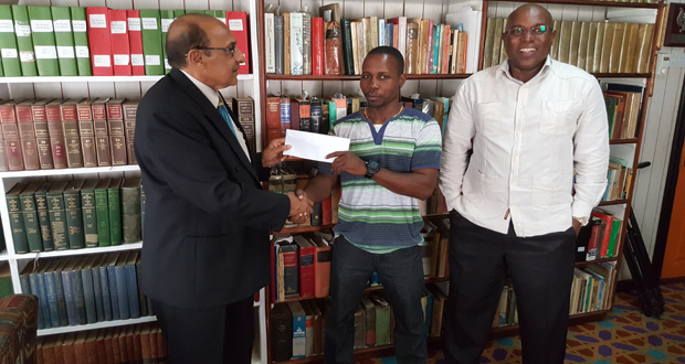 GOA president K.A Juman-Yassin makes a presentation to coach Sebert Blake and president of the GBA Steve Ninvalle..