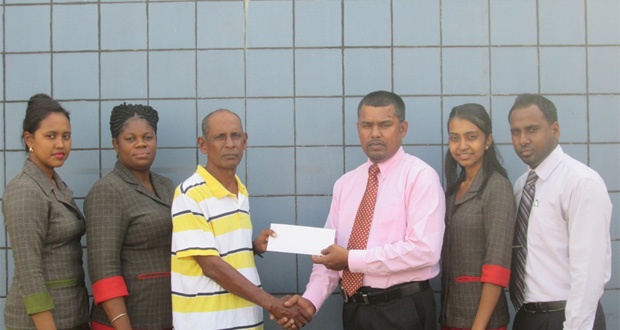 RHTYSC Assistant Organising Secretary, Ravin Kissoonlall receives the sponsorship cheque from Republic Bank RHT Manager Harry Dass Ghaness in the presence of other staff members.