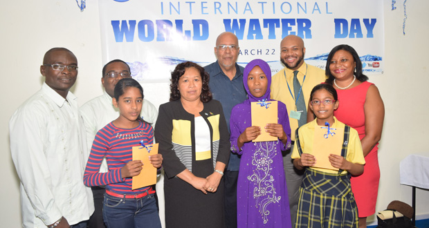 The winners of the essay competition flanked by Minister Dawn Hastings, GWI CEO Dr. Van West Charles, GWI PRO Timothy Austin, and two of the three judges -- Shevion Sears-Murray and Marlon Daniels