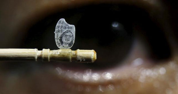 Miniature artist Chen Forng-Shean poses with his latest work, a miniature portrait of Taiwanese president-elect Tsai Ing-wen on a grain of rice, in Taipei, Taiwan April 18, 2016. The Chinese characters read, "Modest, modest and even more modest." (REUTERS/Tyrone Siu)