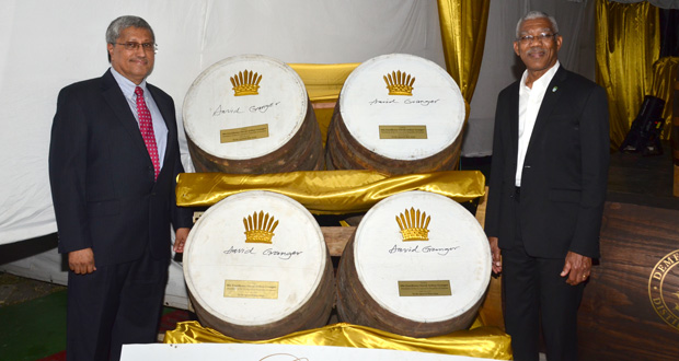 Komal Samaroo, Chairman of DDL, and President David Granger pose for a photo besides casks of 50-year-old rum which will be preserved and bottled in the next 25 years to celebrate Guyana’s 75th Independence Anniversary (Adrian Narine photo)