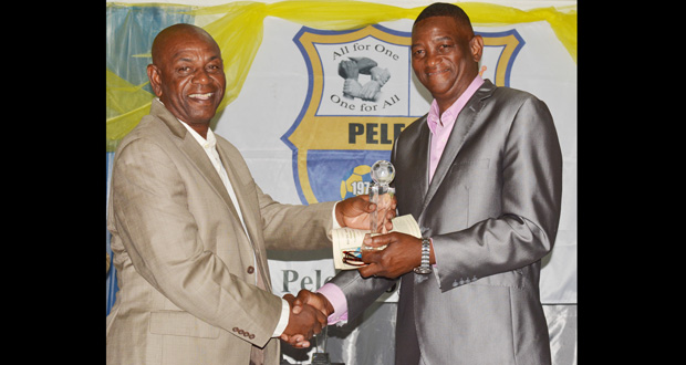 Inductee into the Pele FC Hall of Fame, Dennis `Chow’ Hunte (left), accepts his award from former national player Linden Carter.