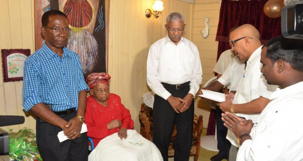 President David Granger with Olive Blackmore as her relatives and members of her church say a prayer