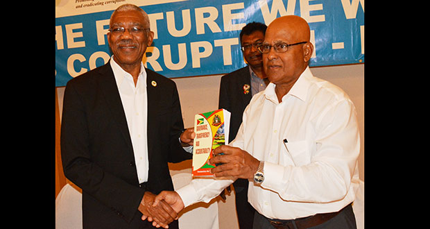 President David Granger is presented with a copy of the book by author Dr Anand Goolsarran