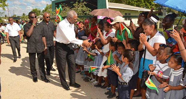 President David Granger interacts with children and parents on April 15,2016, at Kuru Kururu where he commissioned a 72-seater bus to be used to take children to school