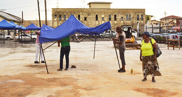 A market vendor walks along the market tarmac as persons set up a tent at the site yesterday afternoon.