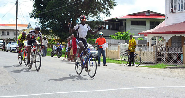 Team Evolution’s Orville Hinds raises his arms in jubilation after winning the first stage of the Golden Jubilee three-stage cycle road race, while Michael Anthony and Junior Niles battle for the minor places (Adrian Narine photo).