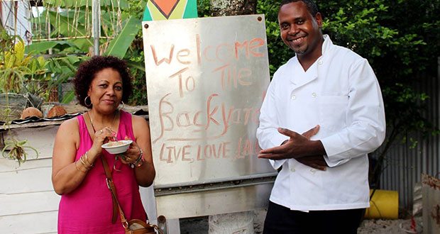 Adams (right) poses with a satisfied customer in front of the unique form of signage at the Backyard Café