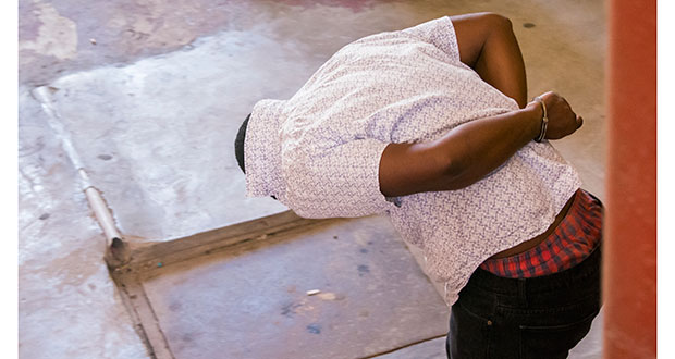 José Barker hides his face as he exits the Georgetown Magistrate's Court.