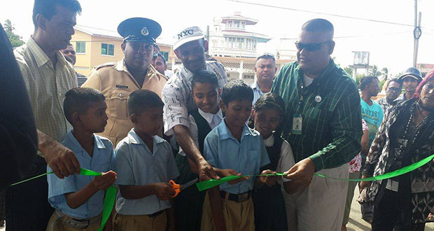 Zakir Ali (in white) is assisted by schoolchildren to officially declare the bus shed open. Looking on at right is the Prime Minister’s Representative in Region Six, Gobin Harbajan