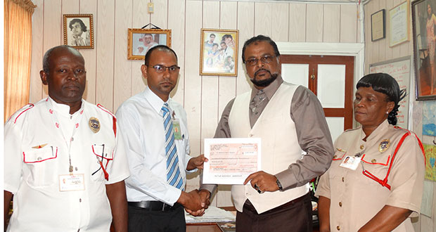 At centre, Mr. Roshan Khan presents cheque to Accountant Derek Sukhram  of Dr. Balwant Singh’s Hospital.  Looking on at left is Security Adviser Colin Boodie and at right – General  Manager, Ingrid Abrams