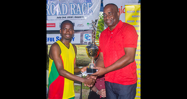 Guyana’s Cleveland Forde is presented with his trophy by Prime Minister of Dominica Roosevelt Skerrit at the completion of CARICOM’s 10K road race. (Samuel Maughn trophy.)