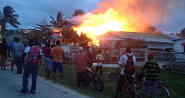 Residents look on as the raging fire destroys the home of Carol Beckles. [Jenell Kishun photo]