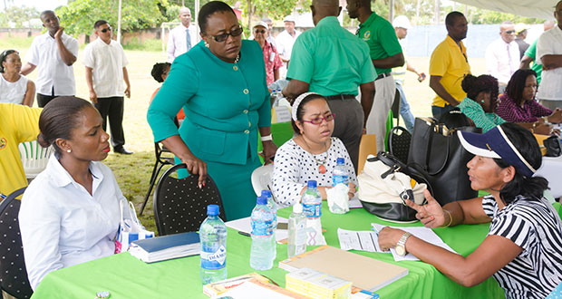 Minister within the Ministry of Natural Resources Simona Broomes and her team listen attentively to a concern raised by a resident during the outreach on Friday (Delano Williams photo)