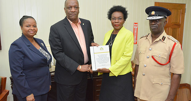 Minister of State, Mr. Joseph Harmon, receiving the report from Commissioner Retired Colonel Windee Algernon (centre right). Minister of Social Protection, Ms. Volda Lawrence, and Acting Chief Fire Winston McGregor (right) also received copies of the report