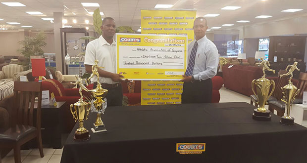 COURTS Marketing Manager Pernell Cummings (left) hands over the cheque to AAG president Aubrey Hutson.