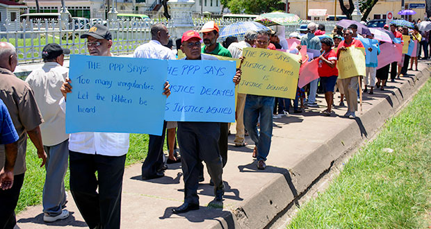 PPP General Secretary Clement Rohee and concerned protestors stand in front of the High Court