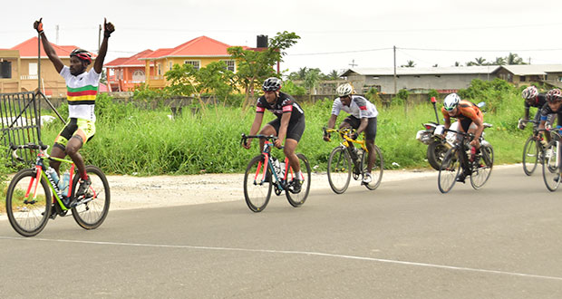 Team Coco’s Junior Niles (left) raises his arms in jubilation as he crosses the finish line to win the PowerAde cycle road race yesterday, in the West Demerara area (photo by Adrian Narine).