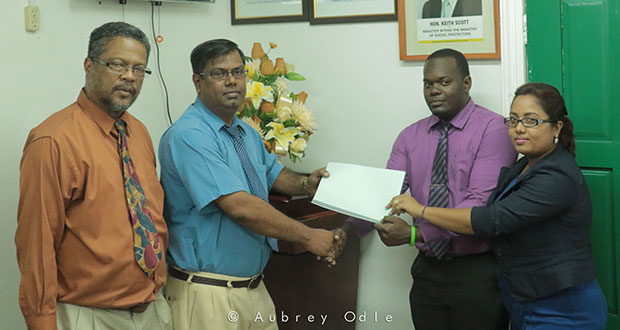 The report from the investigation conducted by Roydon Croal and Radhadevi Takchandra-Singh, Labour, Occupational Safety & Health Officers (right)  was presented to Suresh Singh, General Manager of Tony’s Auto Spares. At left is Chief Labour Officer Charles Ogle. (Aubrey Odle/Ministry of Social Protection photo)